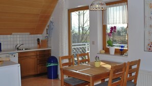 Une cuisine avec des meubles de rangement en bois, un évier et un coin repas comprenant une table et des chaises.