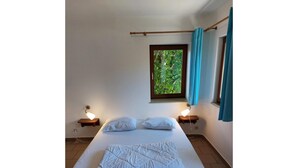 A bedroom with a bed, two bedside tables, a window with curtains, and a view of greenery outside. - Modern Holiday Home with Hot Tub & Sauna in Ardennes (Lierneux)