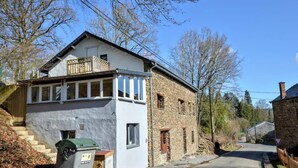 A two-story house with a balcony, a front porch, and a stone exterior. - Modern Holiday Home with Hot Tub & Sauna in Ardennes (Lierneux)