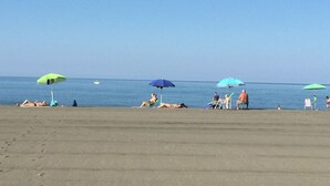 A beach with several umbrellas and people sunbathing. - Apartment in Montalto Near Lake and Pool (Montalto di Castro)