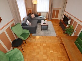 Una sala de estar con sofá, sillas, una mesa de centro y televisor.