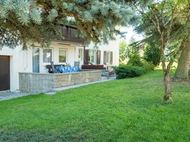 Una casa con patio de piedra, mobiliario exterior y un césped bien cuidado.