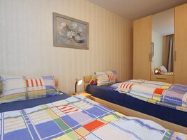 A bedroom with two beds, a nightstand, a lamp, a mirror, and a painting on the wall.