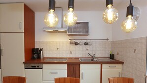 A kitchen with white cabinets, a wooden countertop, a double sink, and four wooden chairs. - Mountain Biker's Farmstay (Villingen-Schwenningen)