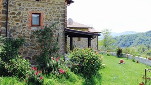 Ein Steinhaus mit Garten, umgeben von Hügeln.