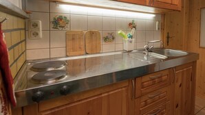 A kitchen with wooden cabinets, a stainless steel sink, and a stove. - Bungalow in Neustadt Nahe Barbarossa Hohle (Harztor)