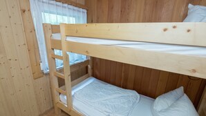 A bunk bed room with wooden walls and a window with white curtains. - Bungalow in Neustadt Nahe Barbarossa Hohle (Harztor)