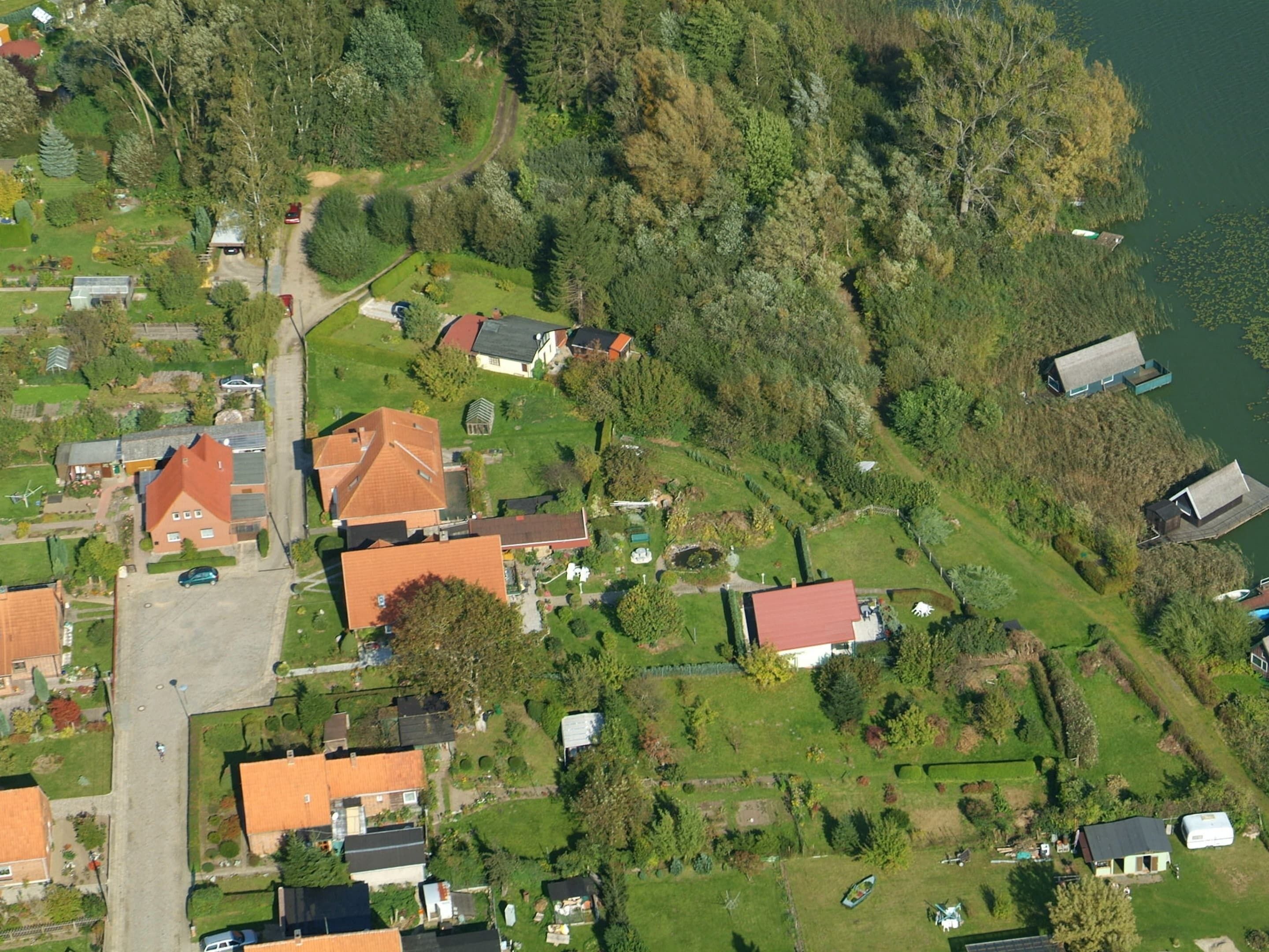 Eine Vogelperspektive eines Wohngebiets mit Häusern, grünen Rasenflächen und einem See.