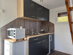 A compact kitchen with a built-in oven, a sink, and a dishwasher. - Bootshaus Direkt am See mit Eigenem Steg an der Ostsee (Sternberg)