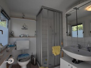 A bathroom with a toilet, sink, and shower. - Bootshaus Direkt am See mit Eigenem Steg an der Ostsee (Sternberg)
