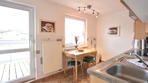 Una cucina con tavolo e sedie, termosifone, una finestra con vista e un lavello.