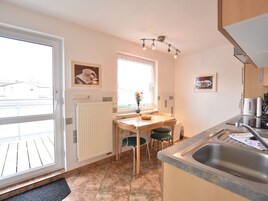 Una cocina con una mesa de comedor, sillas, un radiador, una ventana con vistas y un lavabo.