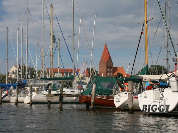A marina with multiple boats docked, a church in the background, and a clear sky. - Schone Wohnung mit Balkon Nahe Ostseestrand in Rerik (Rerik)