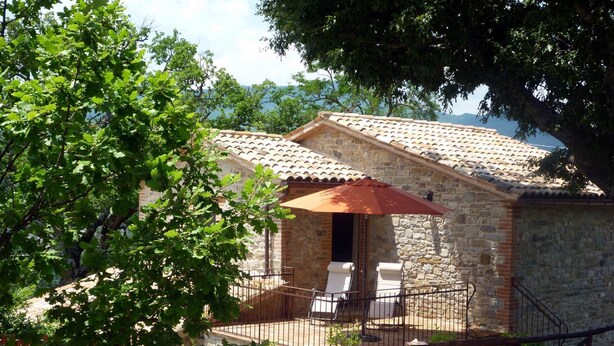 A stone building with a tiled roof, a covered patio with two chairs, and a staircase leading to the entrance. - Apartment in Pennabili on Tuscan Border near Nature Park (Pennabilli)