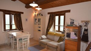 A cozy room with a dining table, a sofa, a cabinet, and a kitchen area with an oven. - Apartment in Pennabili on Tuscan Border near Nature Park (Pennabilli)