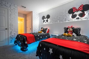 Ein Schlafzimmer mit zwei Betten, jedes mit einem Mickey Mouse-Kopfstück, einer roten Decke und einem Mickey Mouse-Plüschtier.