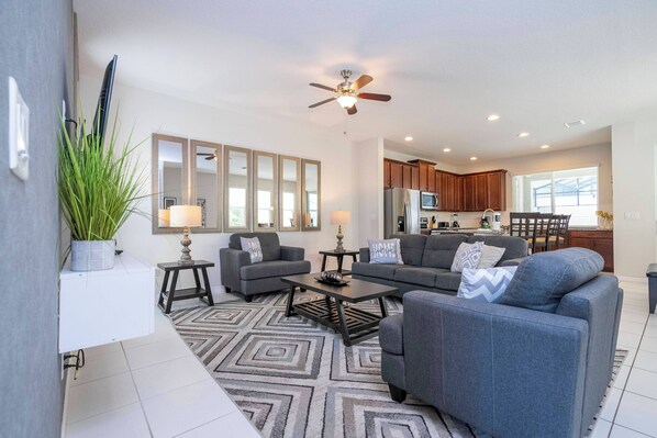 A modern living room with grey sofas, a coffee table, and a large mirror. - Solara Resort 4BD Pool Home, Perfect Location 1554 (Kissimmee)