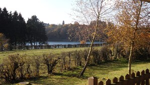 Une vue d’un vignoble avec une clôture en bois au premier plan et un lac en arrière-plan.