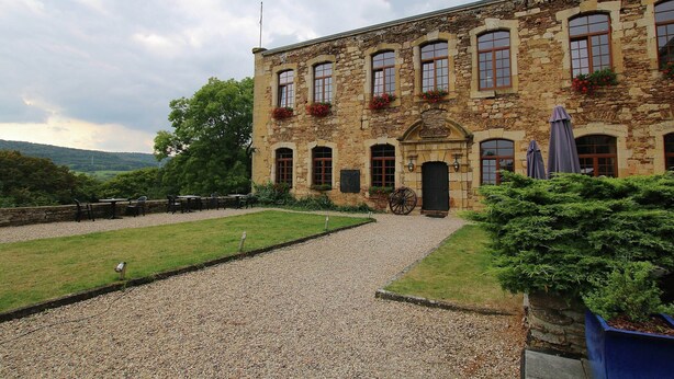 A stone building with multiple windows, a gravel driveway, and outdoor seating. - Unique Holiday Home in Virton with Hot Tub (Habay)