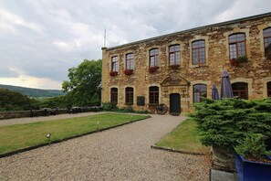 A stone building with multiple windows, a gravel driveway, and outdoor seating. - Unique Holiday Home in Virton with Hot Tub (Habay)