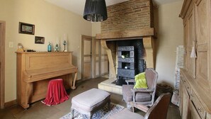 A room with a fireplace, wooden furniture, a piano, and a hanging light fixture. - Unique Holiday Home in Virton with Hot Tub (Habay)