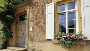 A stone building with a wooden door, white shutters, and a flower box on the window sill. - Unique Holiday Home in Virton with Hot Tub (Habay)