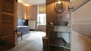 A bathroom with a wooden door, a sink with a mirror, a towel rack, and a window with blinds. - Unique Holiday Home in Virton with Hot Tub (Habay)