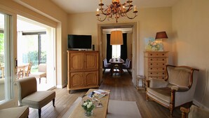 A living room with a chandelier, wooden furniture, a television, and a dining area in the background. - Unique Holiday Home in Virton with Hot Tub (Habay)