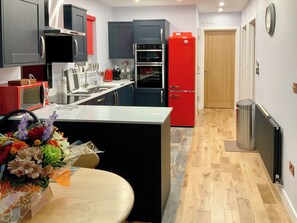A modern kitchen with grey and red cabinets, a central island, and a red refrigerator. - Tidereach - Otters View - UK12269 (Connel, near Oban)