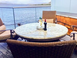 A round table with a marble top on a balcony, surrounded by wicker chairs. - Tidereach - Otters View - UK12269 (Connel, near Oban)