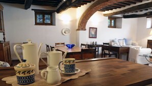 A kitchen with a wooden countertop, a dining table, and chairs. There are ceramic coffee pots and cups on the counter. - Cozy Holiday House With Terrace (Castiglion Fiorentino)