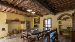 Uma cozinha rústica com uma grande mesa de madeira, bancos e uma lareira de pedra.