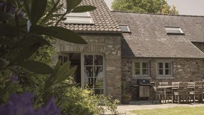 A stone building with a tiled roof, a covered entrance, and outdoor seating. - Cottage in Haut-bois With Private Pool (Gesves)