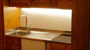 A compact kitchen with wooden cabinets, a stainless steel sink, and a dishwasher. - Contemporary Apartment in Breuil-Cervinia near Ski Area (Valtournenche)