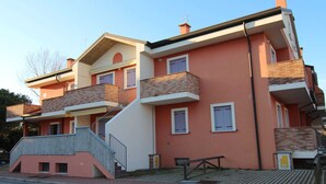 A multi-story residential building with balconies, a staircase, and a small outdoor seating area. - Sun Drenched Residence with Pool in Rosolina Mare near Venice (Rosolina)