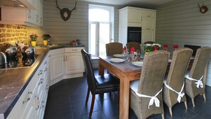 Een keuken met een eethoek, met een stenen muur, houten kastjes en een tafel gedekt voor vier personen.