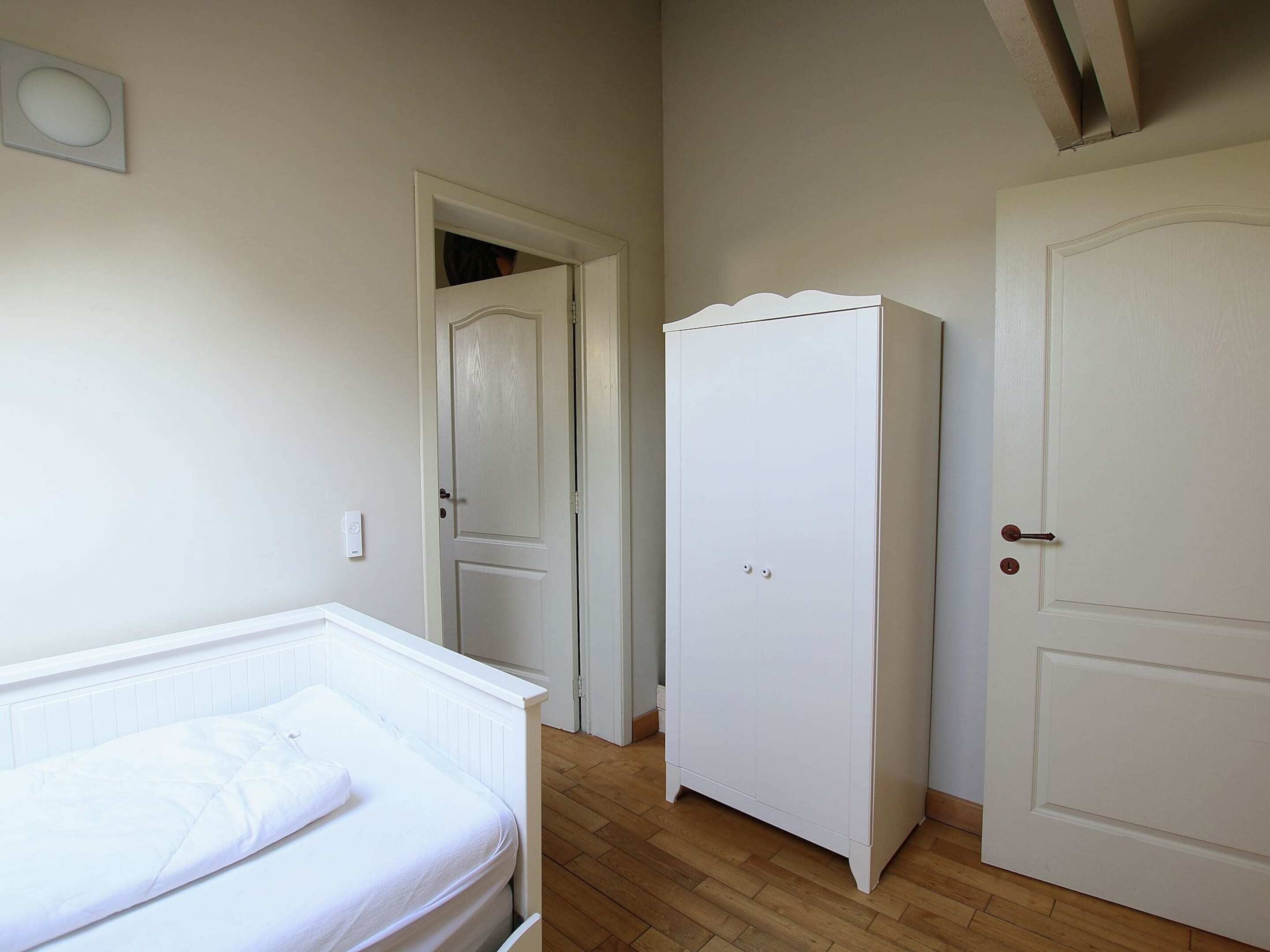 Een slaapkamer met een bed, een kledingkast en een deur.