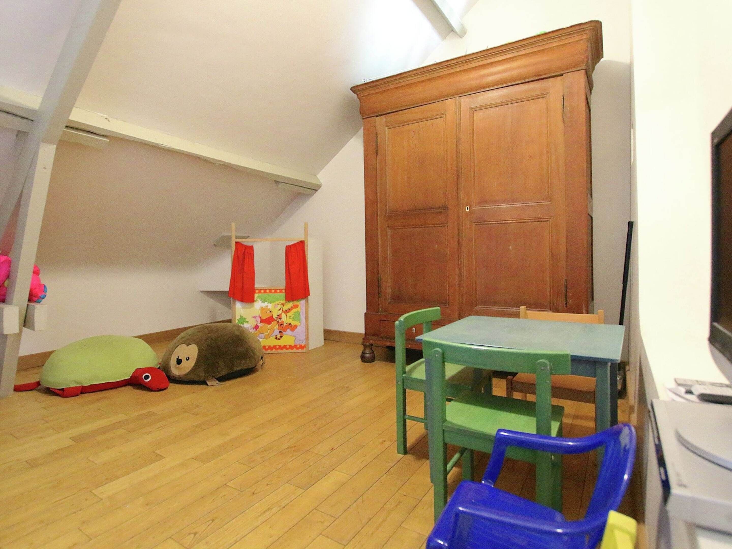 Un área de juegos infantiles con un mueble de madera, una mesita y sillas.