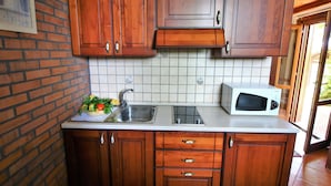A kitchen with wooden cabinets, a tiled backsplash, a stainless steel sink, and a white microwave. - Holiday Home in Sabina With Saltwater Pool (Selci)