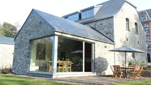 A stone building with a glass extension, outdoor seating, and a gravel area. - Forestview Family Home (Gesves)