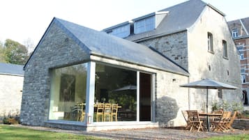 A stone building with a glass extension, outdoor seating, and a gravel area.