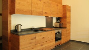 A kitchen with wooden cabinets, a sink, a coffee maker, a microwave, and an oven. - Forestview Family Home (Gesves)