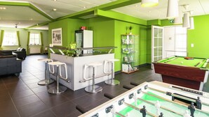 Espaço moderno com mesa de bilhar, bar e área de estar.