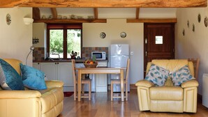 A cozy living area with a kitchen, featuring a dining table, two sofas, and a refrigerator. - Round House - UK12083 (St Endellion, near Port Isaac)