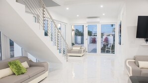 Amplia sala de estar con una escalera moderna, un sofá y un televisor.