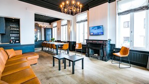 A modern interior with a dining area, sofa, fireplace, and large windows.