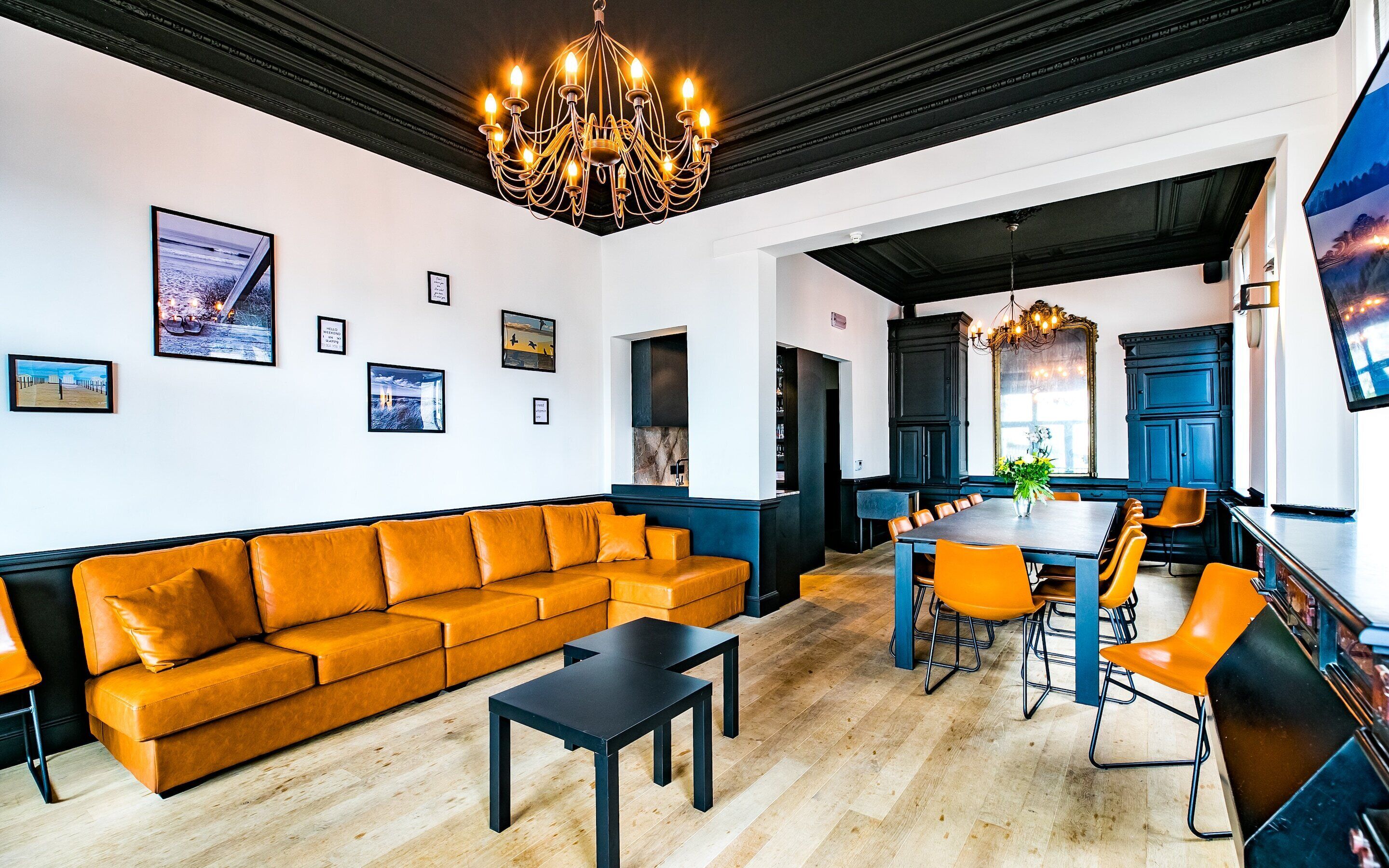 A modern hotel lobby with a sofa, dining table, chairs, and a chandelier.
