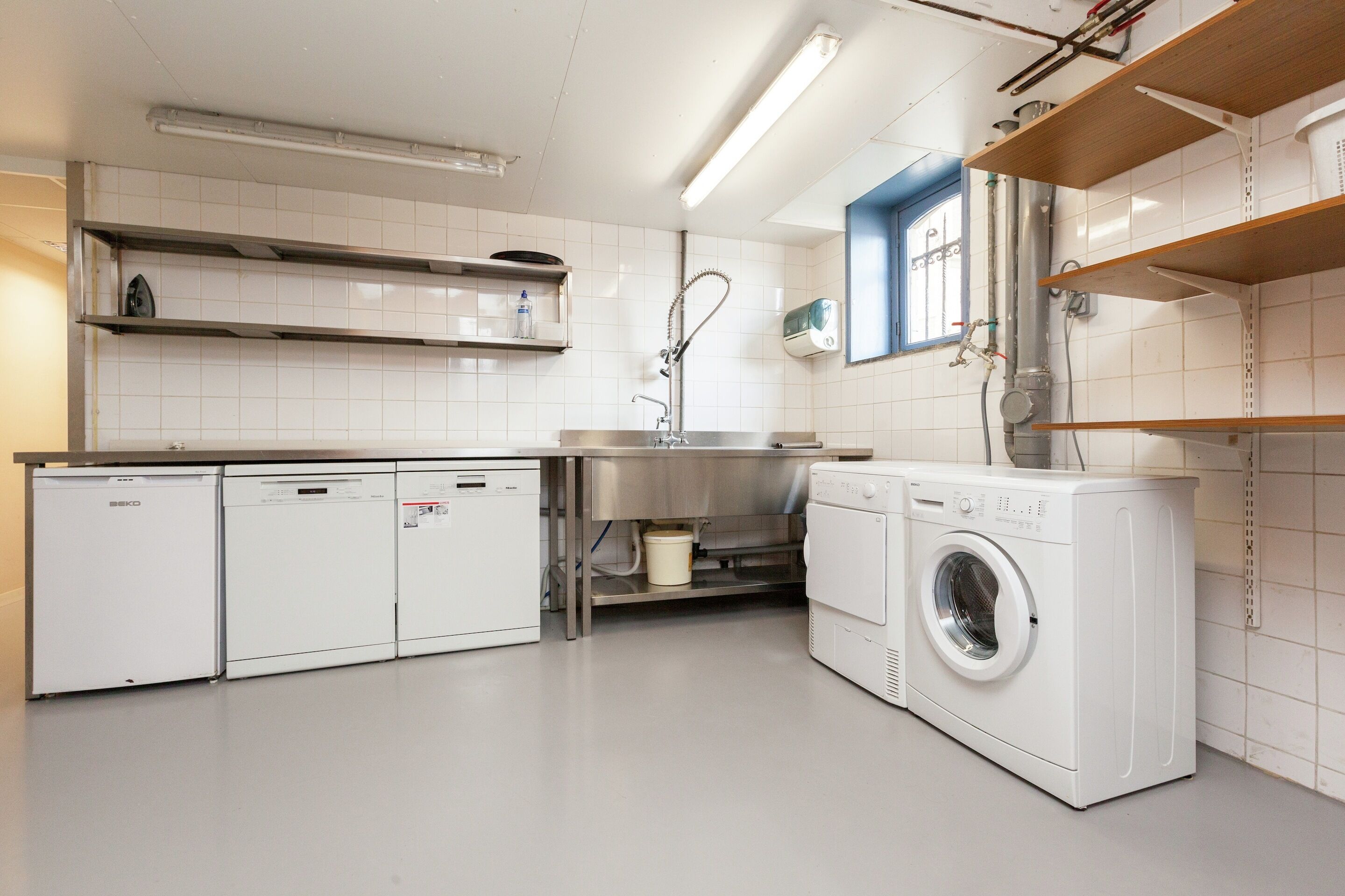 Une cuisine moderne équipée d’appareils électroménagers intégrés, notamment un lave-vaisselle, une machine à laver et un évier.