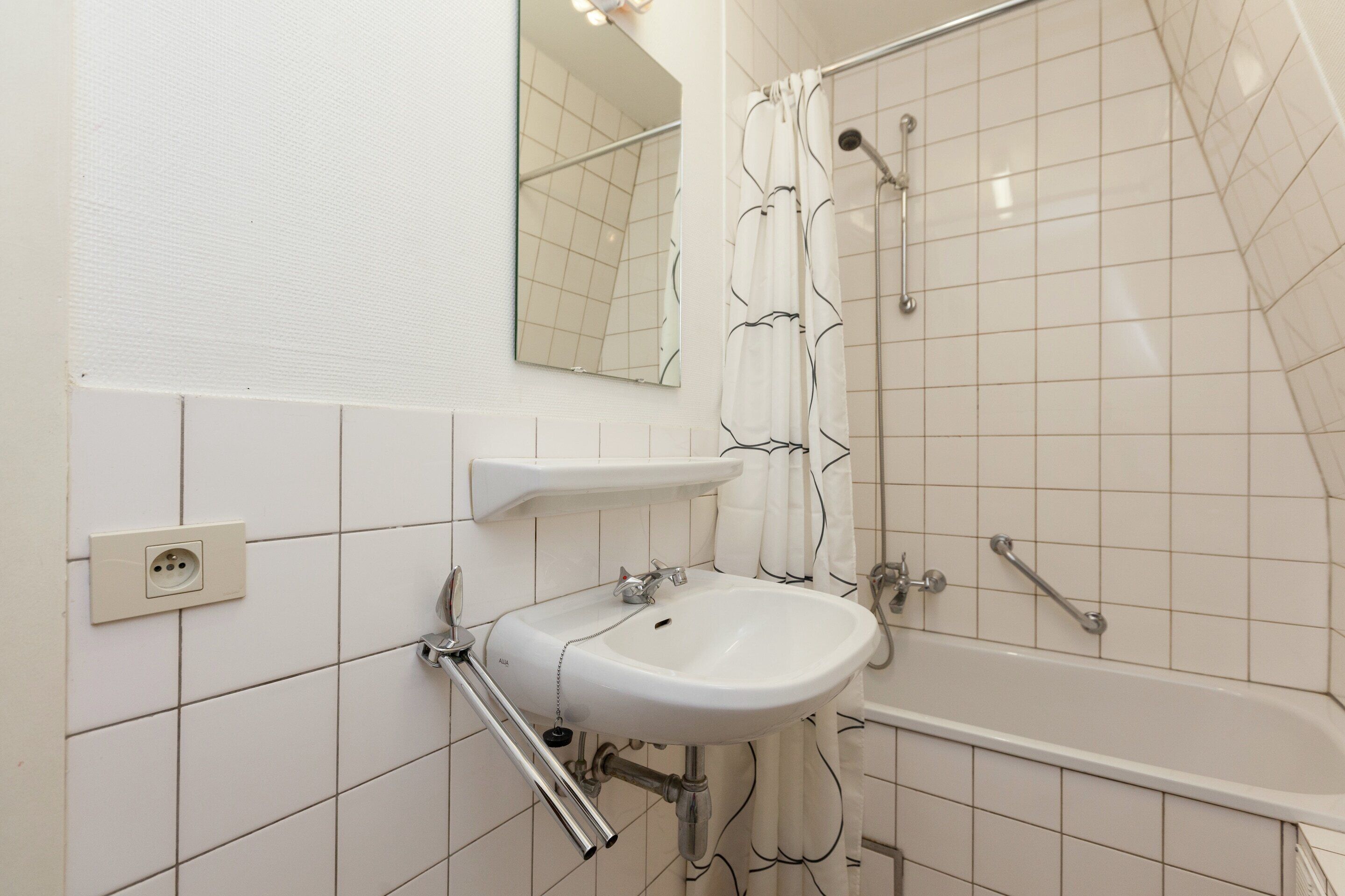 A bathroom with a white sink, mirror, and bathtub.