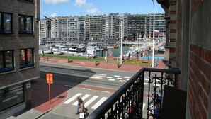 A view of a marina with boats, a pedestrian crossing, and high-rise buildings in the background.